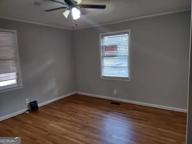 an empty room with wooden floor and windows