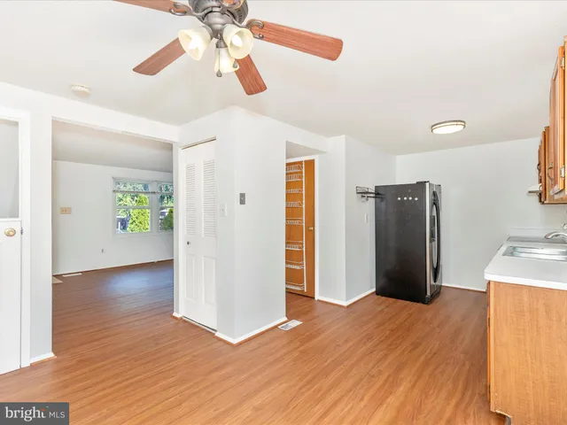 a view of a kitchen with a refrigerator a ceiling fan and wooden floor
