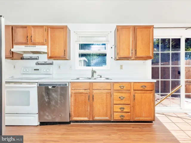a kitchen with stainless steel appliances granite countertop a sink and cabinets with wooden floor