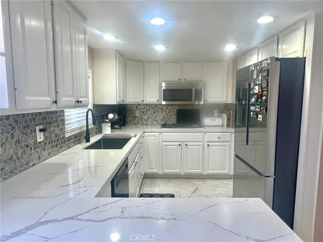 a large kitchen with a refrigerator a sink a stove a microwave and cabinets
