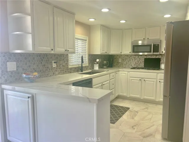 a kitchen with a sink a counter top space cabinets and stainless steel appliances