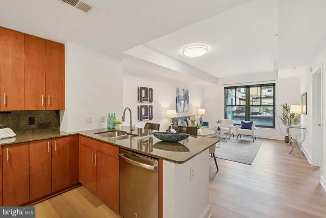 a open kitchen with stainless steel appliances granite countertop a sink dishwasher stove and wooden cabinets with wooden floor