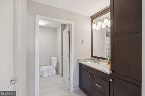 a bathroom with a granite countertop sink a toilet and a mirror