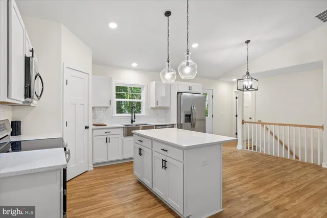 a kitchen with white cabinets sink and stainless steel appliances
