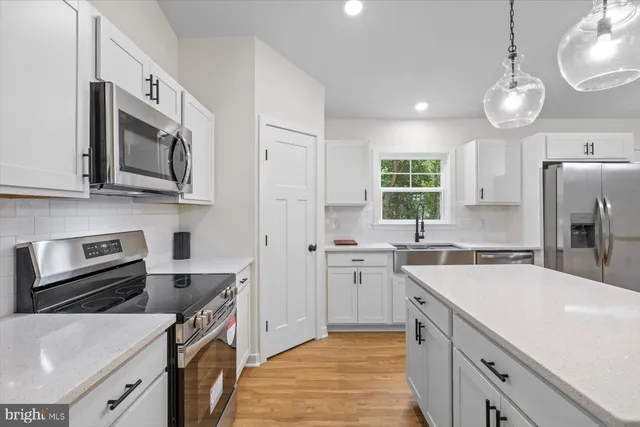 a kitchen with stainless steel appliances granite countertop a sink stove microwave and refrigerator