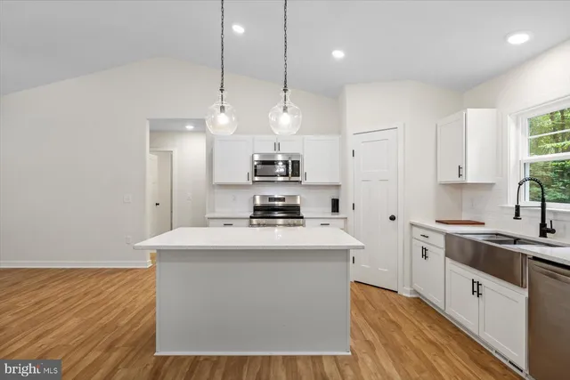 a kitchen with kitchen island a sink stainless steel appliances and cabinets