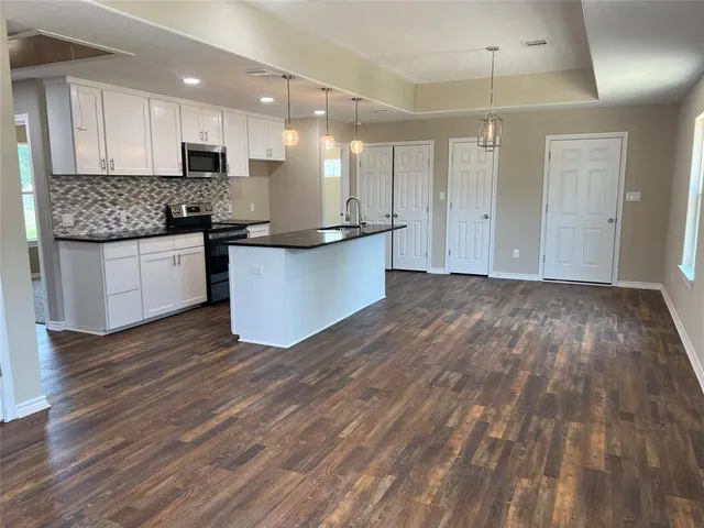 a large kitchen with hardwood floor a sink stainless steel appliances and cabinets