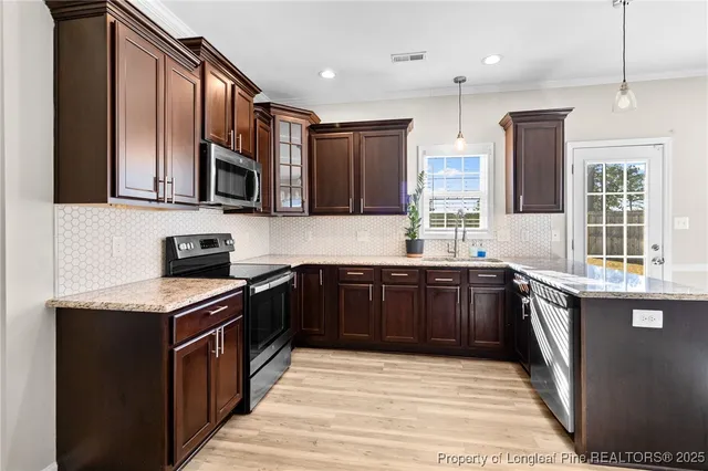a kitchen with stainless steel appliances granite countertop a stove sink microwave and window