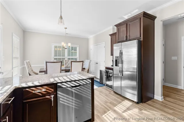 a kitchen with stainless steel appliances granite countertop a refrigerator a stove a sink dishwasher and a refrigerator with wooden floor