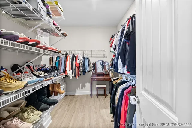 a view of walk in closet with clothes and shoes