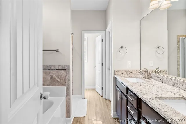 a bathroom with a granite countertop sink a mirror and a bathtub