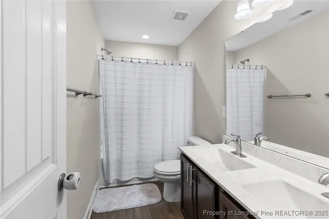 a bathroom with a sink toilet double vanity and shower