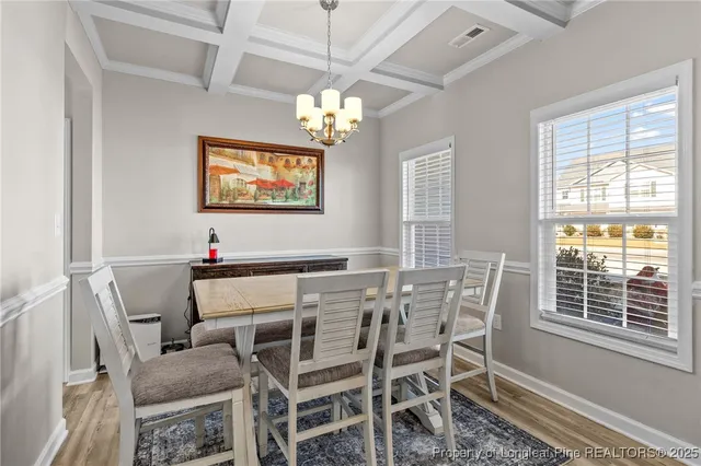 a view of a dining room with furniture a chandelier and a window