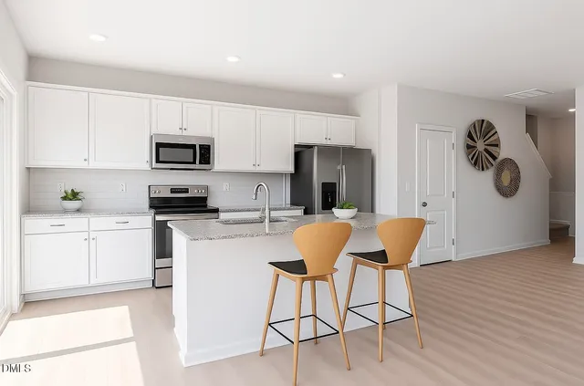 a kitchen with stainless steel appliances a refrigerator stove microwave and white cabinets with wooden floor