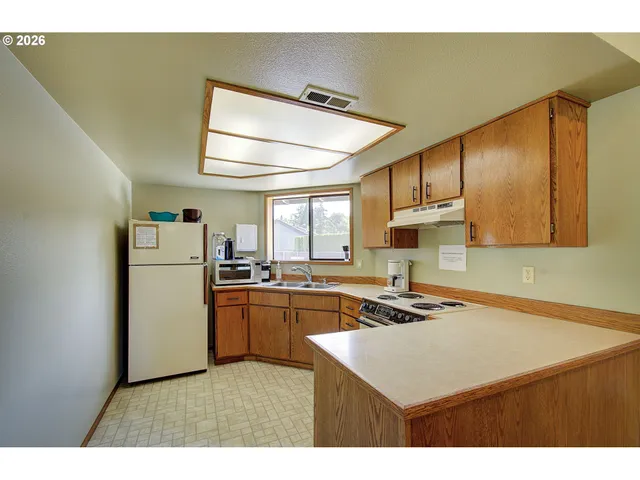 a kitchen with a refrigerator a sink dishwasher and a stove with wooden floor