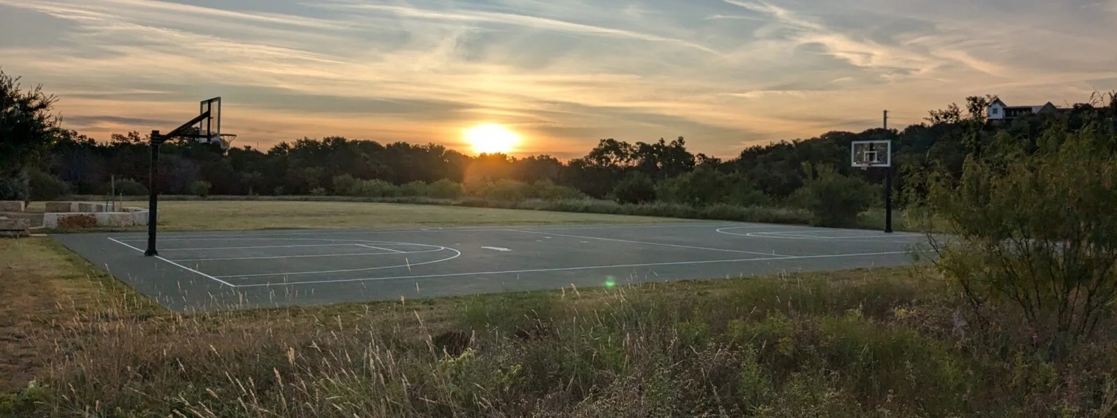 169 Marcheeta Way Leander, TX 78641 - Photo 33 of 39 Basketball court with two hoops, surrounded by grassy areas and distant trees