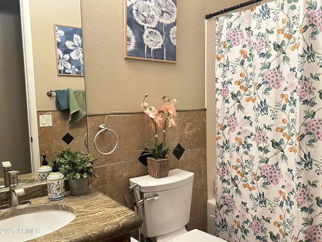 a bathroom with a granite countertop sink and a toilet