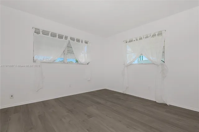 an empty room with wooden floor and fan