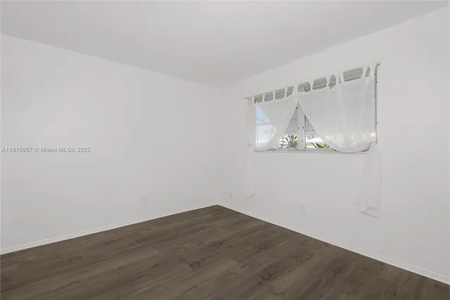 an empty room with wooden floor and white walls