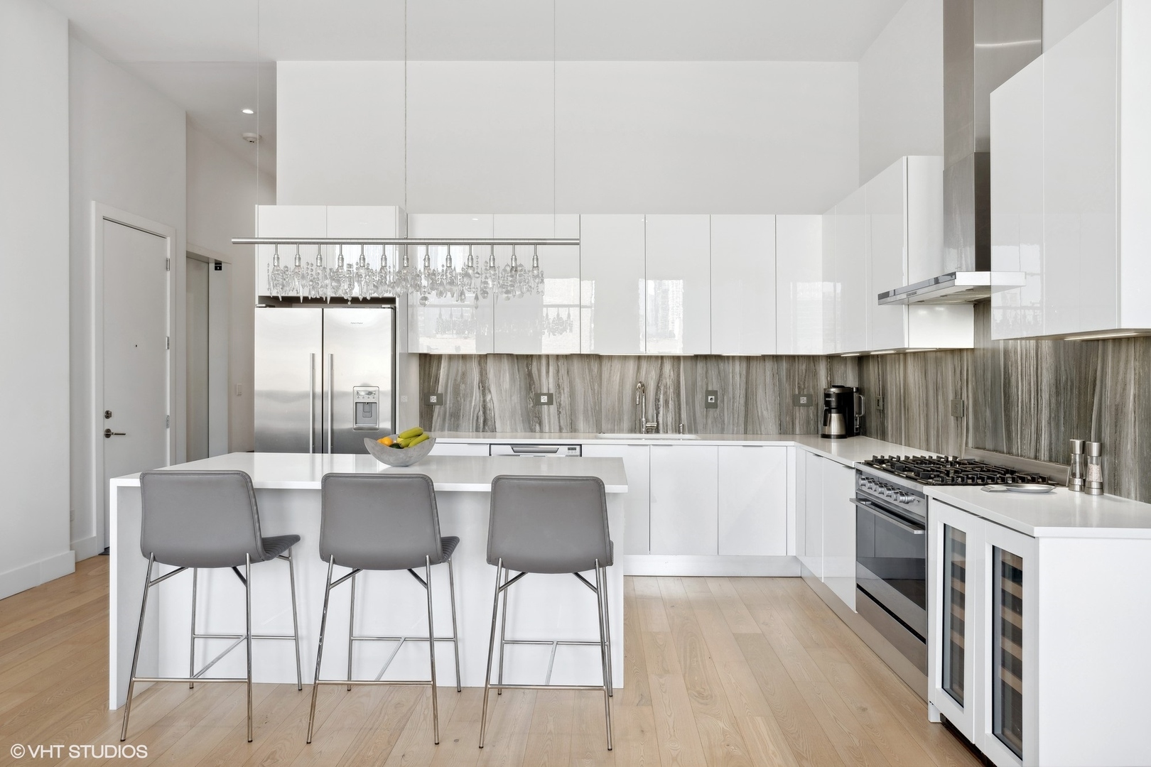 128 South Aberdeen Street, Unit PHN Chicago, IL 60607 - Photo 10 of 43 a kitchen with stainless steel appliances a stove a sink a refrigerator and white cabinets with wooden floor