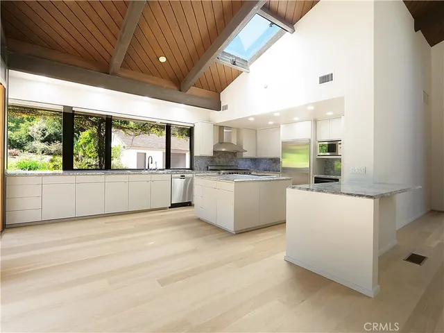 a large white kitchen with a large window a sink and white cabinets