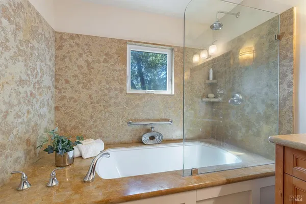 a bathroom with a tub a sink and glass door