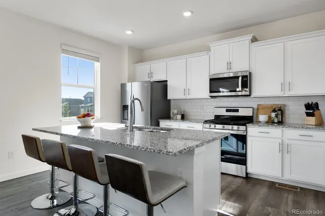 a kitchen with stainless steel appliances granite countertop a stove a sink a microwave a dining table and chairs