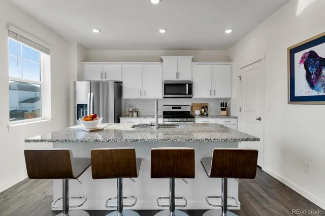 a kitchen with stainless steel appliances granite countertop a stove a refrigerator a sink a stove with island and chairs