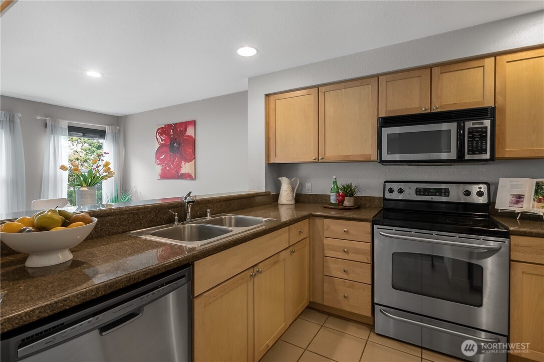 1311 12th Avenue South, Unit D202 Seattle, WA 98144 - Photo 8 of 20 a kitchen with granite countertop kitchen island stainless steel appliances a stove sink and microwave