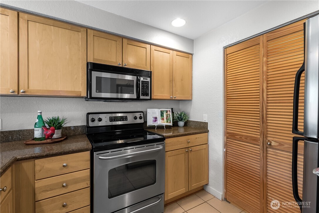 1311 12th Avenue South, Unit D202 Seattle, WA 98144 - Photo 10 of 20 a kitchen with granite countertop cabinets stainless steel appliances and a window
