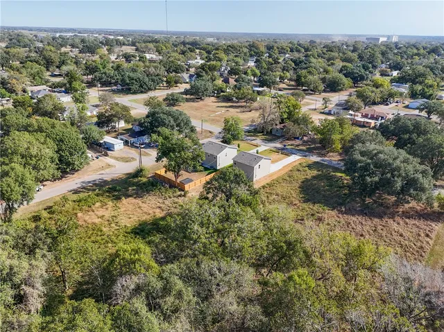 an aerial view of residential houses with outdoor space and trees