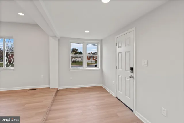 an empty room with wooden floor and windows