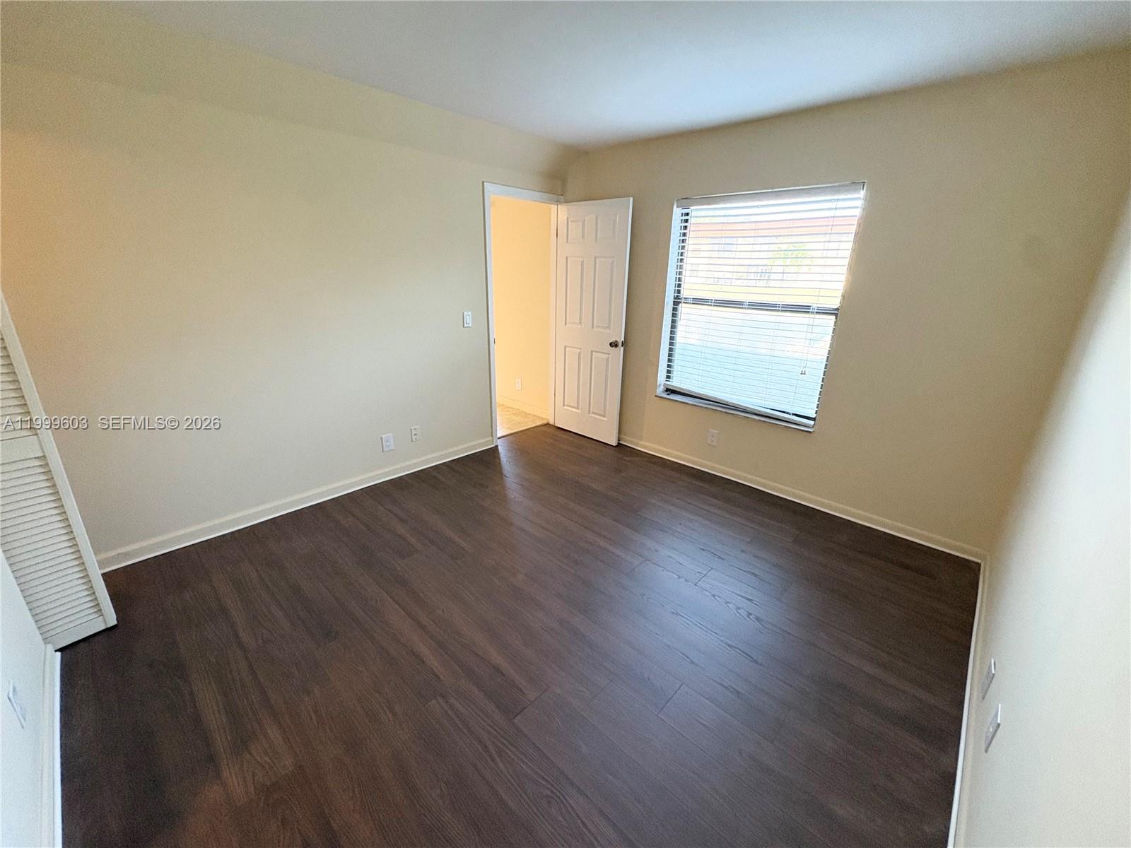 21904 Lake Forest Circle, Unit 203 Boca Raton, FL 33433 - Photo 6 of 11 an empty room with wooden floor and windows