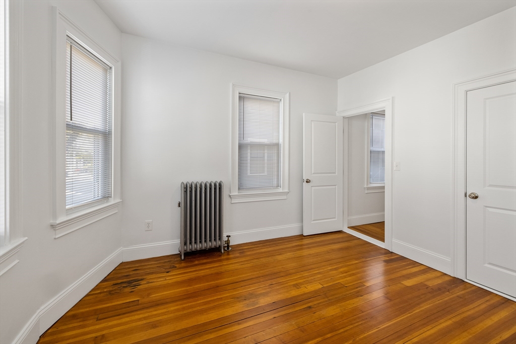 122 Columbia Street, Unit 3 Cambridge, MA 02139 - Photo 7 of 17 an empty room with wooden floor and windows