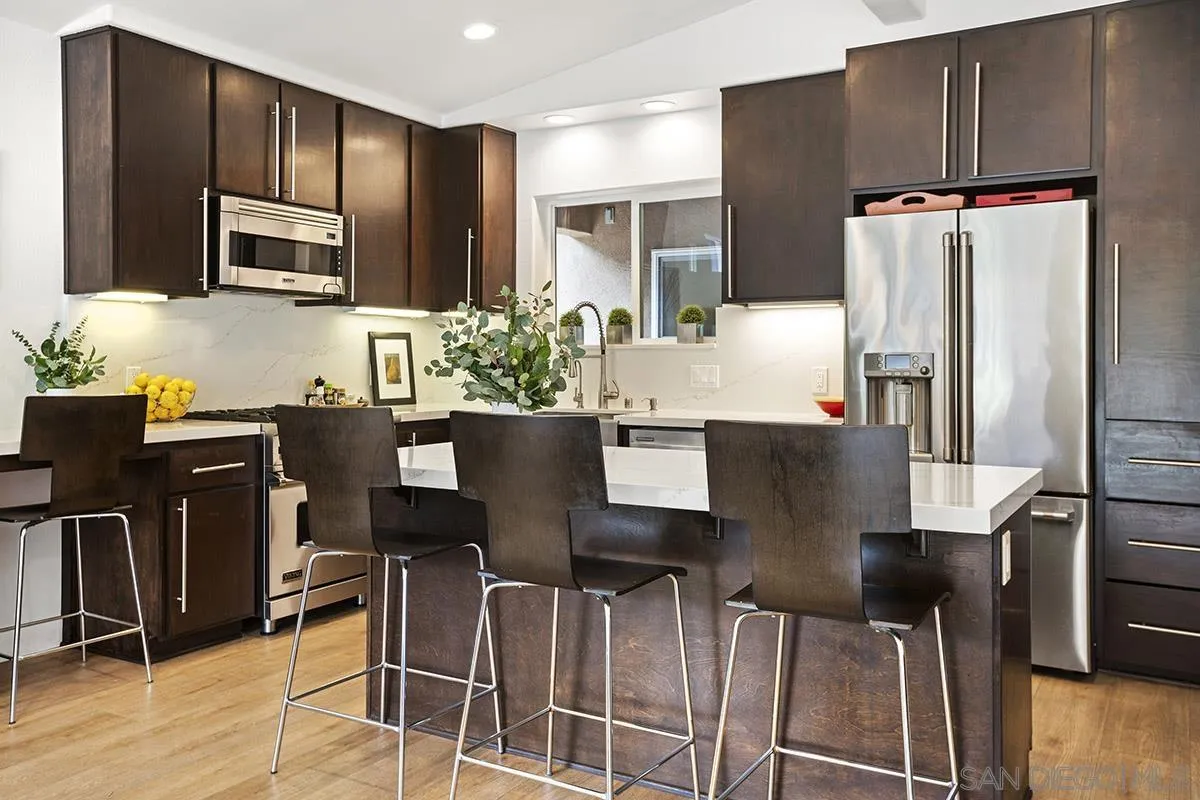 3433 Alabama Street San Diego, CA 92104 - Photo 18 of 58 a kitchen with stainless steel appliances kitchen island granite countertop a table chairs microwave and sink
