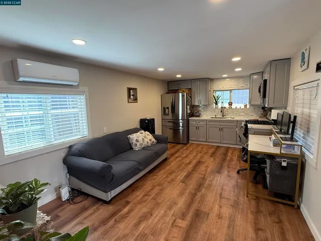 a living room with stainless steel appliances furniture and a wooden floor