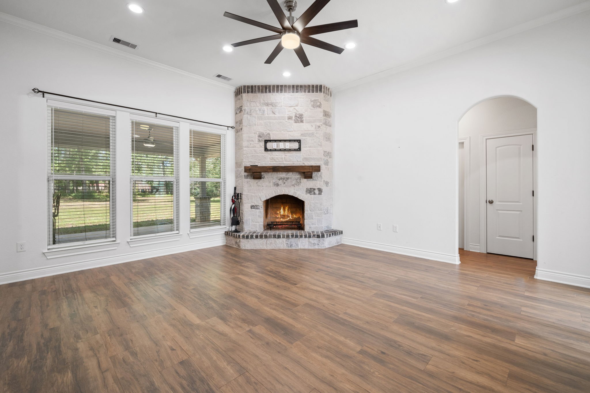 7815 Timber Switch Road Cleveland, TX 77328 - Photo 18 of 39 Spacious living room featuring a cozy stone fireplace, elegant hardwood floors, and large windows that flood the space with natural light.