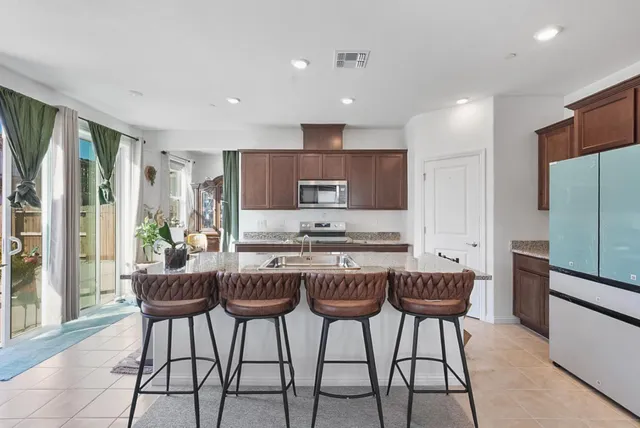 a kitchen with stainless steel appliances kitchen island granite countertop a refrigerator and a stove top oven