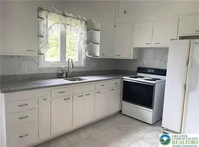 a kitchen with granite countertop white cabinets and white appliances