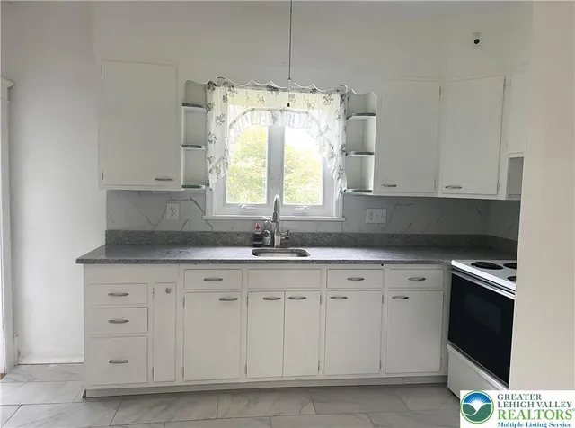 a kitchen with granite countertop white cabinets and a sink