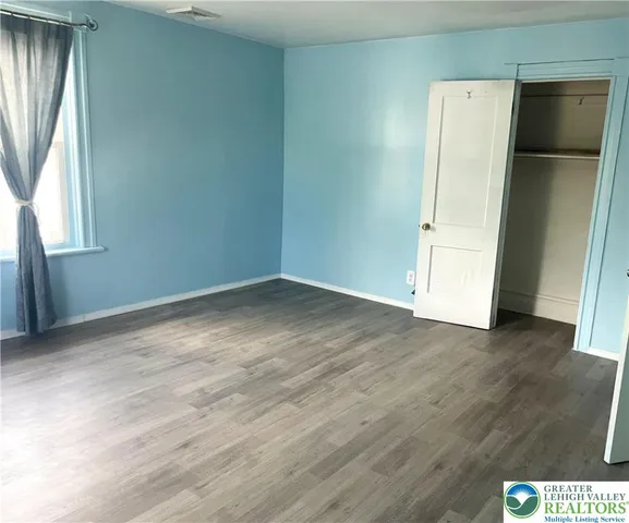 an empty room with wooden floor and window