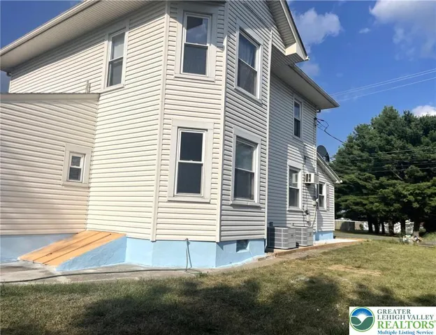 a view of a white house with a yard and lawn chairs