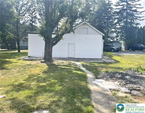 a view of a house with a yard and large tree