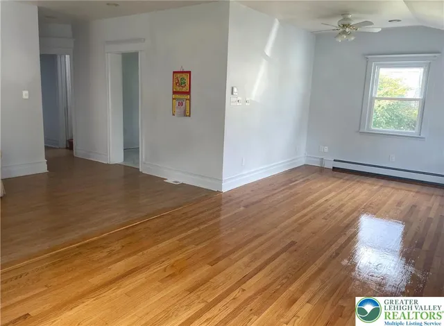 an empty room with wooden floor mirror and windows