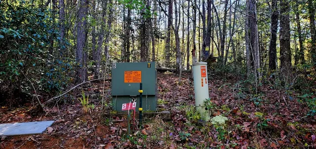 a sign board with a house and trees in the background