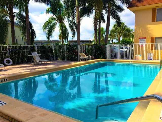a view of a swimming pool with a lawn chairs under palm trees