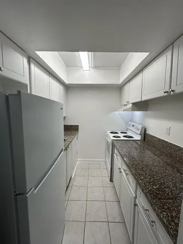 a kitchen with granite countertop a refrigerator and a sink