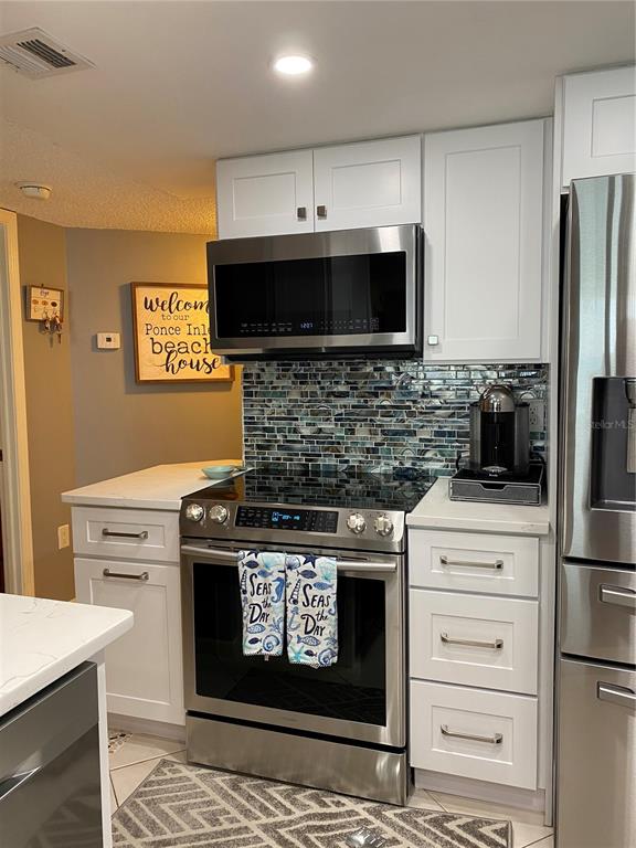 4453 South Atlantic Avenue, Unit 208 Ponce Inlet, FL 32127 - Photo 38 of 40 a kitchen with stainless steel appliances a stove a microwave and a refrigerator