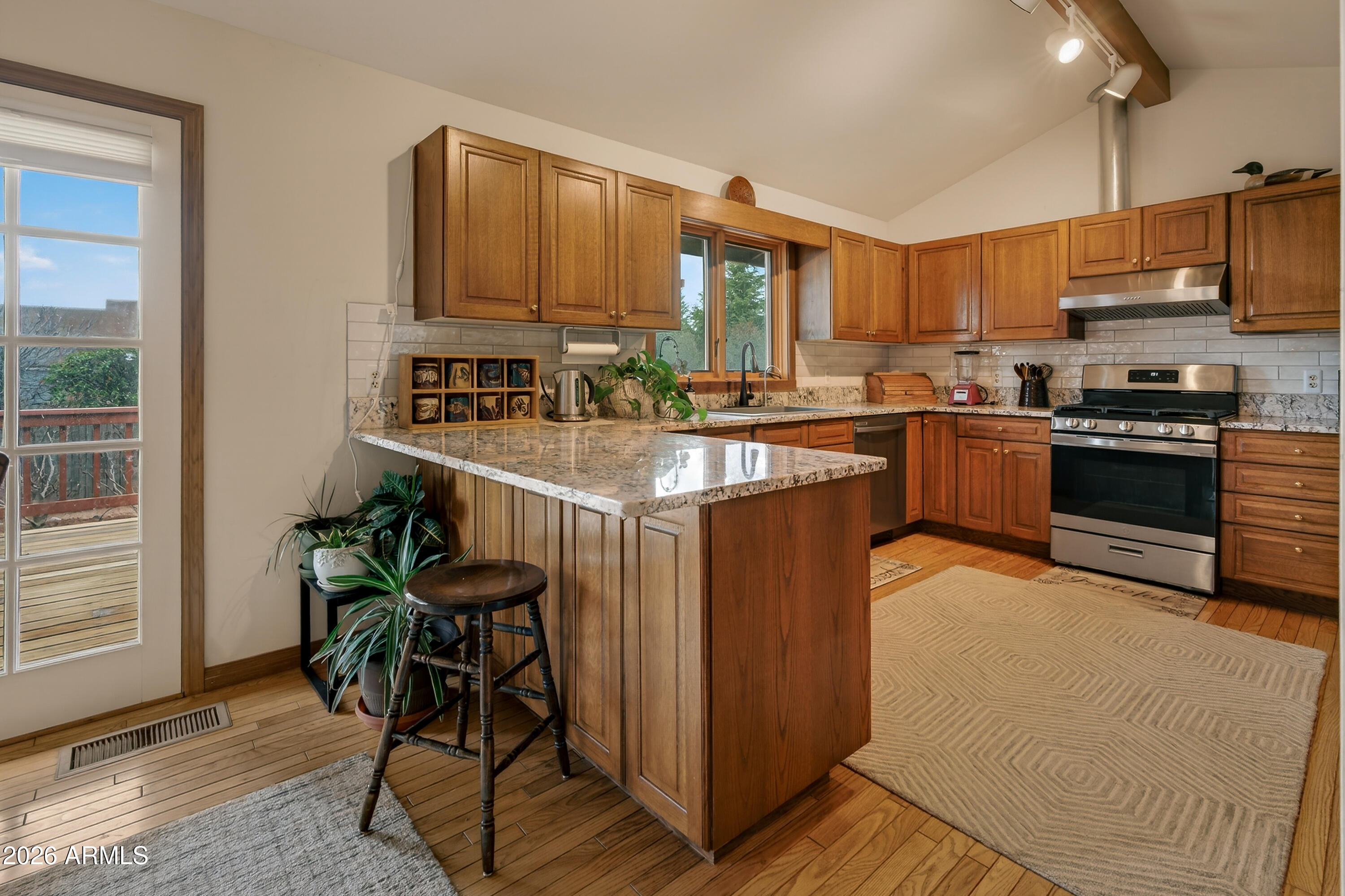 2215 Lariat Road Sedona, AZ 86336 - Photo 19 of 45 a kitchen with stainless steel appliances granite countertop a stove top oven a sink dishwasher a dining table and chairs with wooden floor