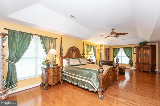 a bedroom with a bed couch and a large window with wooden floor